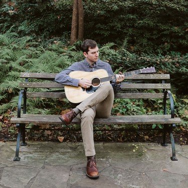 Reagan playing guitar on a garden bench