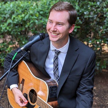 Reagan Leonard in a suit with his guitar in a garden