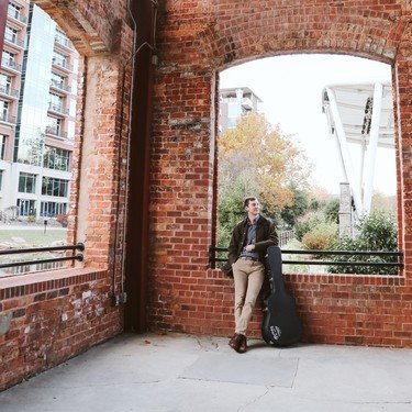 Reagan with his guitar in a brick alcove